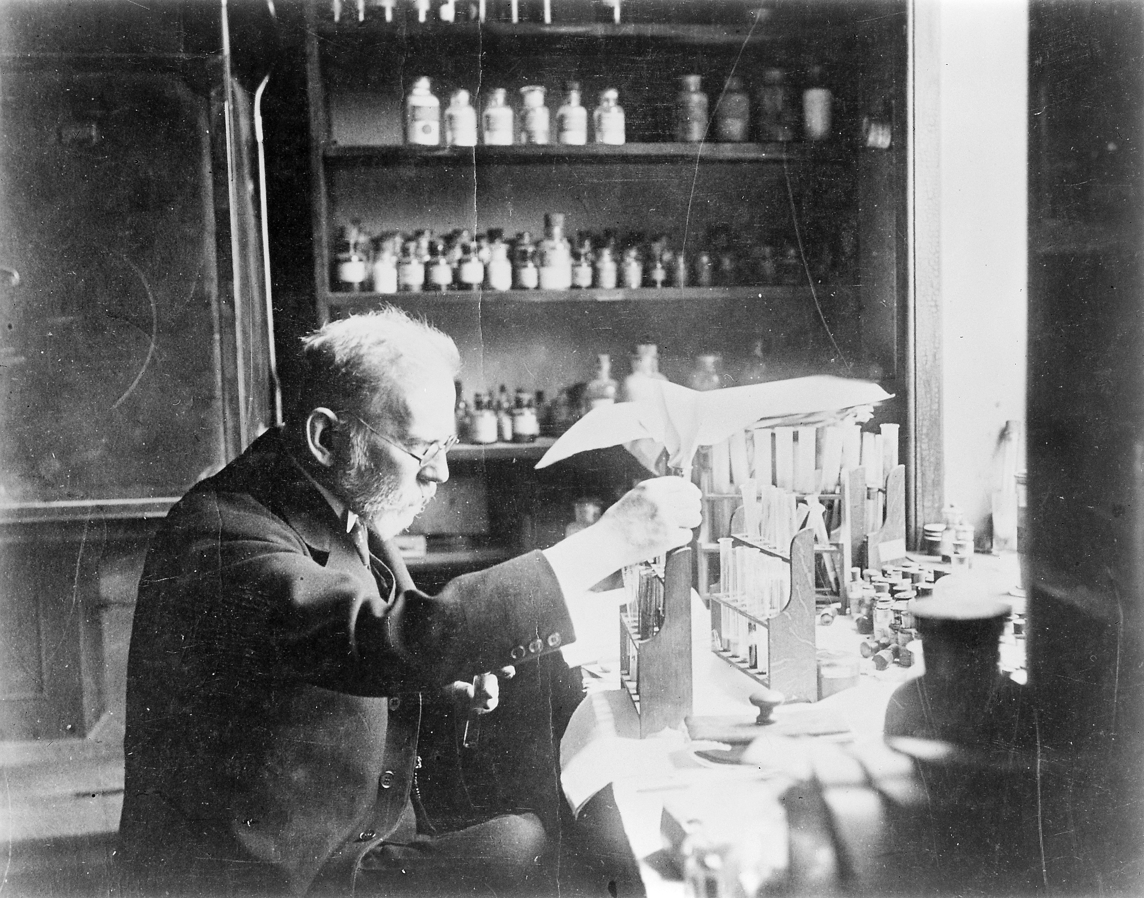Paul Ehrlich seated at a laboratory bench, working with glassware.
